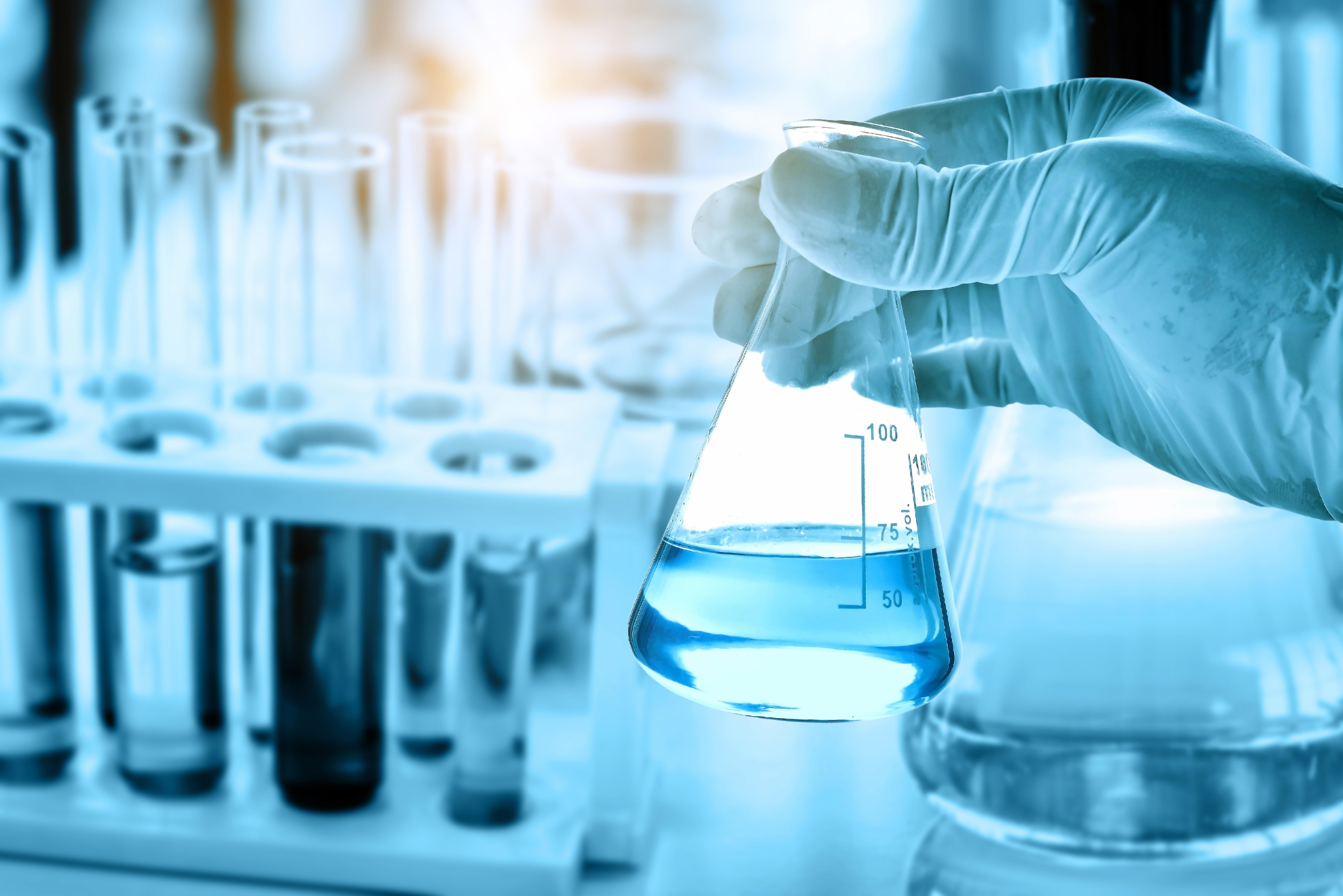 hand-of-scientist-holding-flask-with-lab-glassware-in-chemical-laboratory-background_8100-x-5407-px