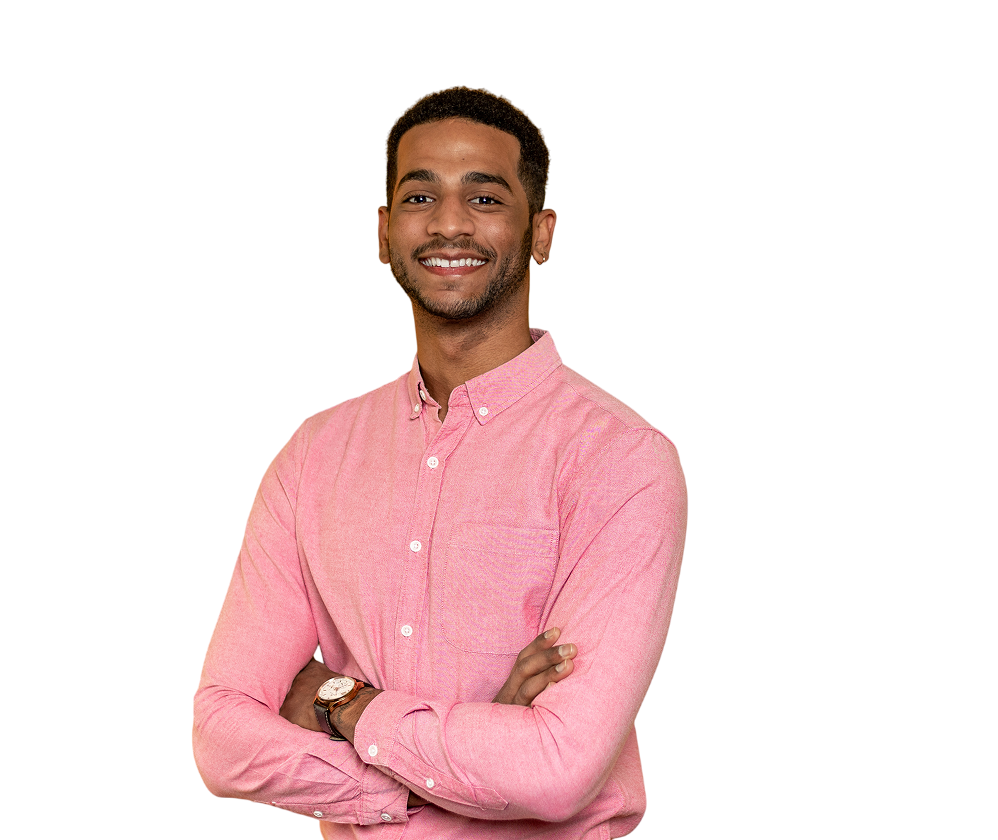 A man smiling directly at the camera.  The man is wearing a pink shirt and has his arms crossed. 