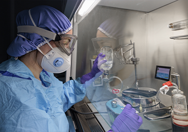 Microbiology technician performing sterility testing inside a controlled aseptic environment, using sterile tools and culture media.