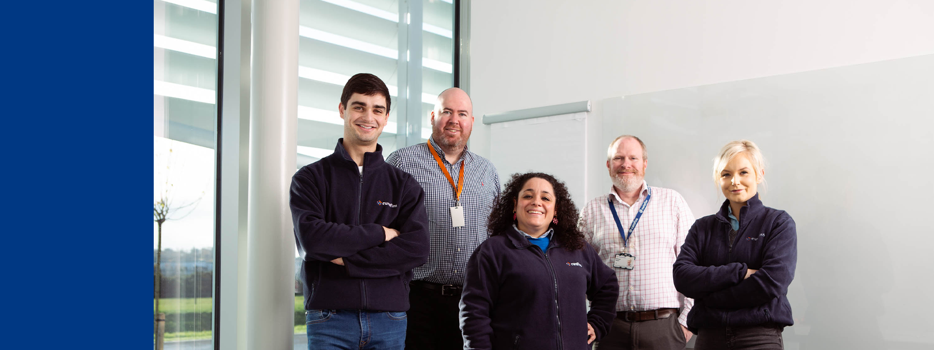 Five members of the MDS Consulting team standing in a bright office with large windows and a whiteboard, faces blurred for privacy, representing expert support in Quality Assurance, Regulatory Affairs, and PRRC services.