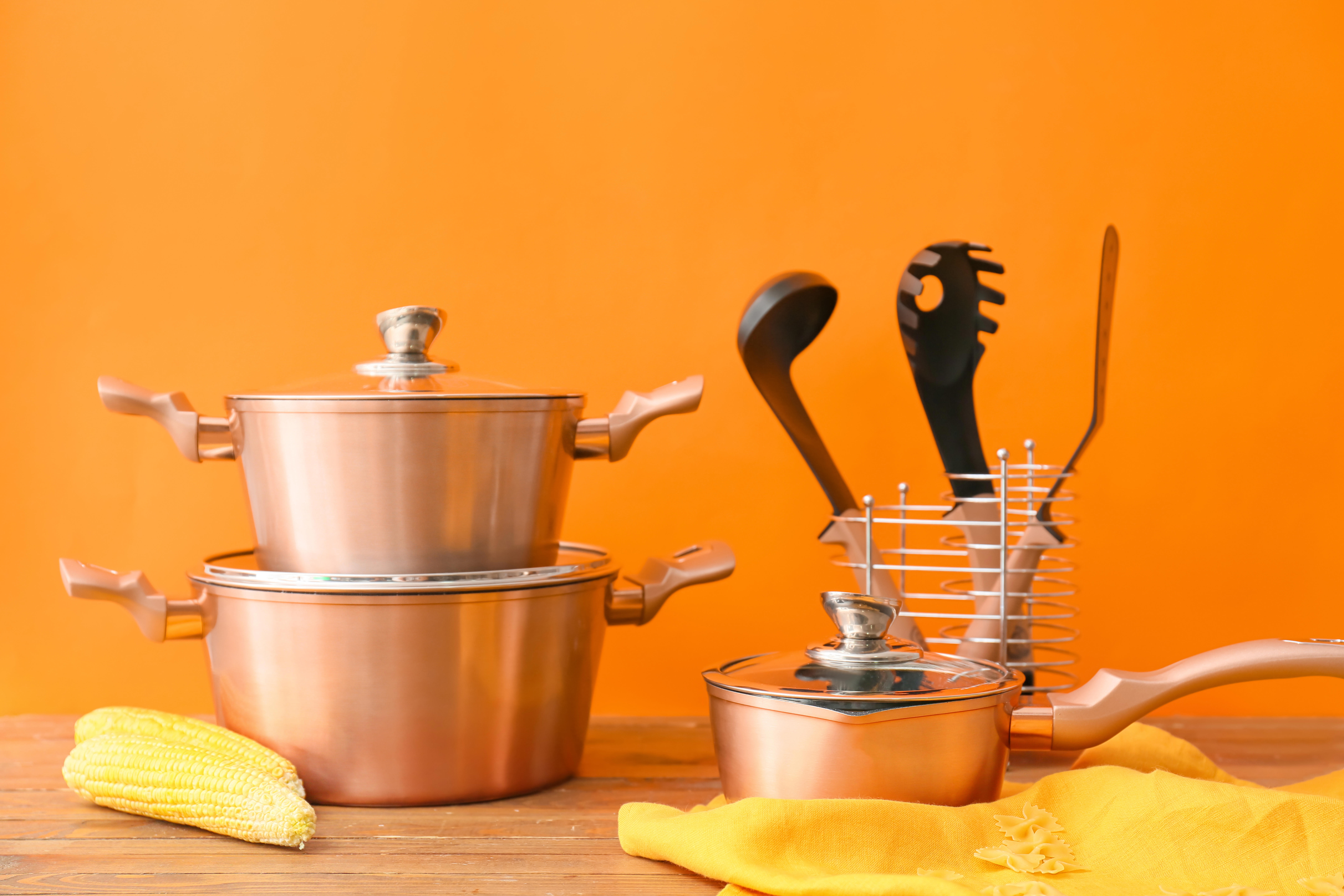 copper-kitchen-utensils-and-raw-food-on-table-against-orange-background_8640-x-5760-px