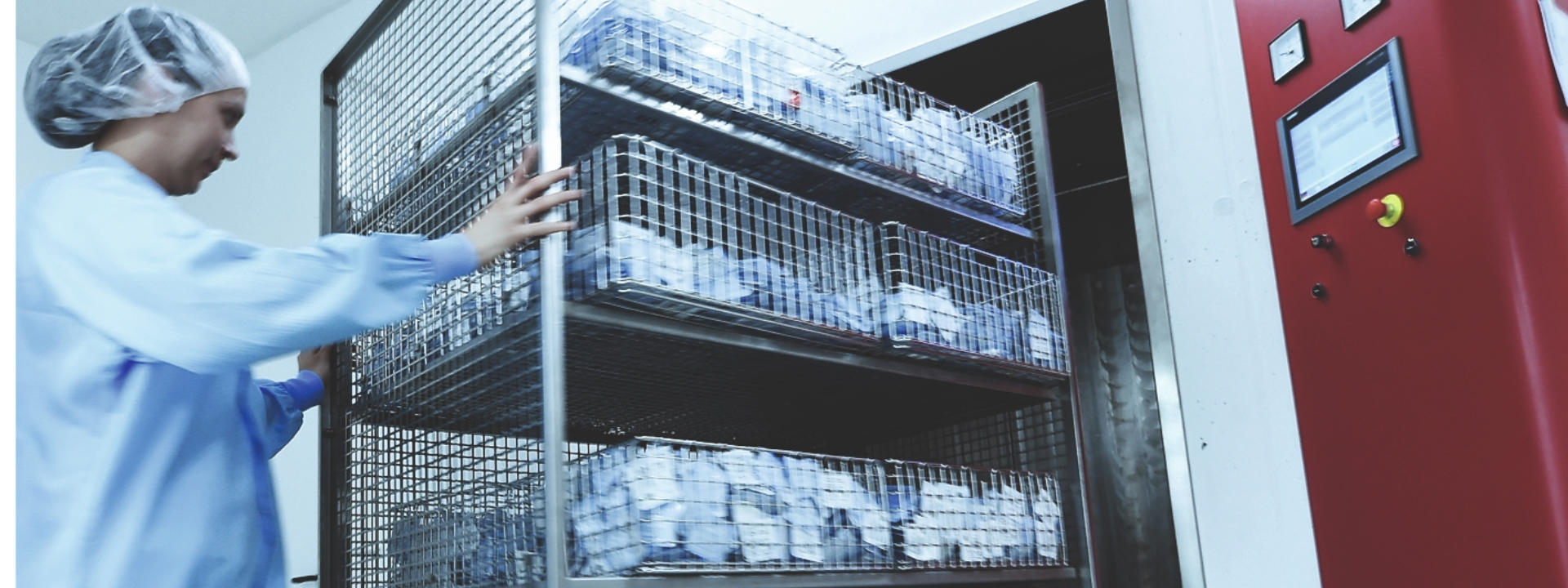 Technikerin schiebt einen Wagen in eine EO-Sterilisationskammer zur Sterilisation von Medizinprodukten.