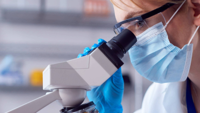close-up-of-female-lab-worker-wearing-ppe-and-safety-glasses-looking-at-slide-under-microscope_5184-x-7776-px1