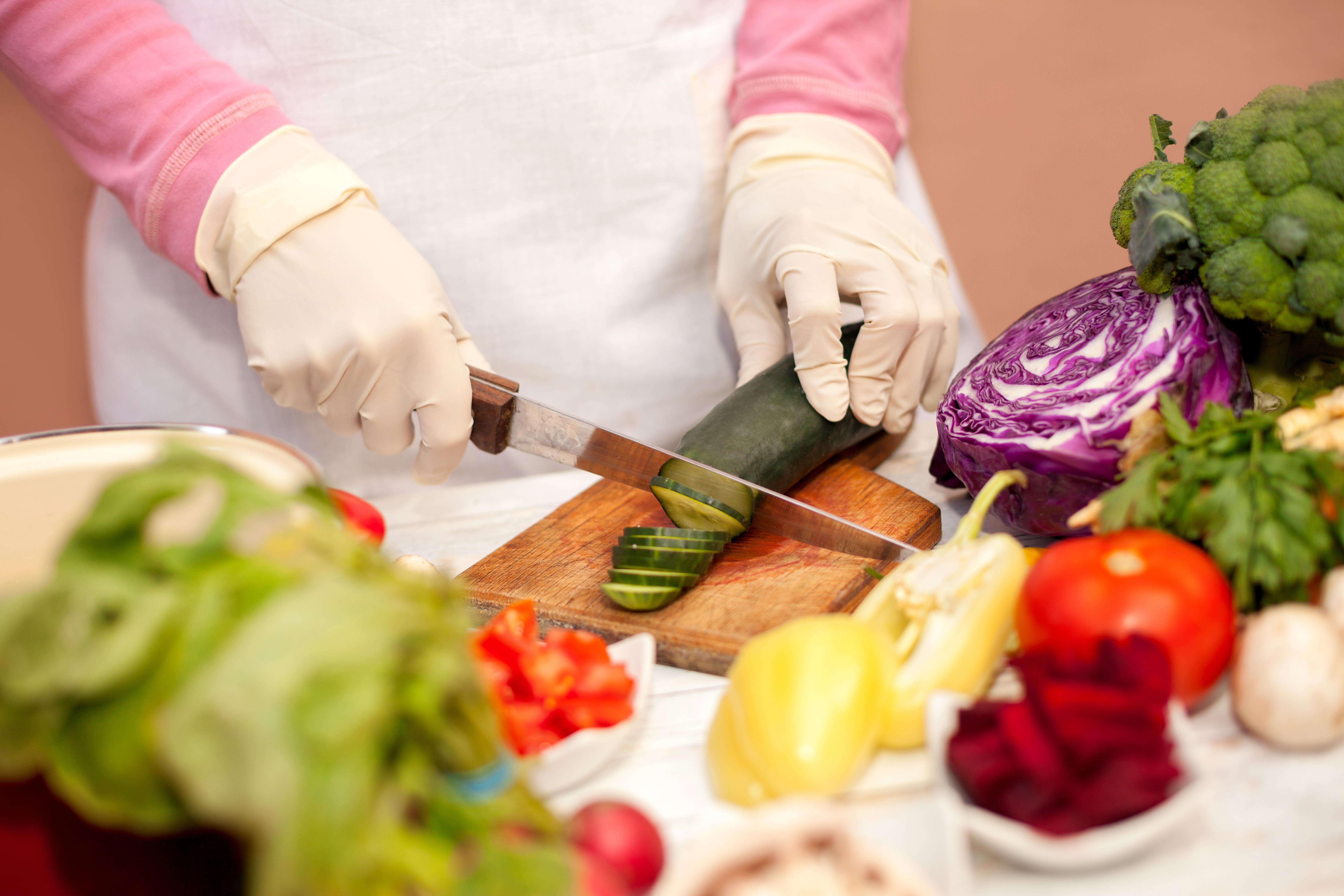 woman-with-white-glove-slicing-cucumber-with-a-knife-on-chopping-board_-8424-x-5616-px