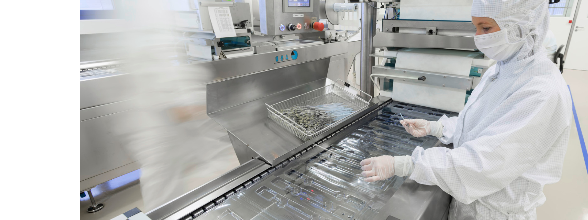 Produktionsmaschine zur Herstellung steriler Blisterverpackungen, im Hintergrund Mitarbeitende in Reinraumkleidung.