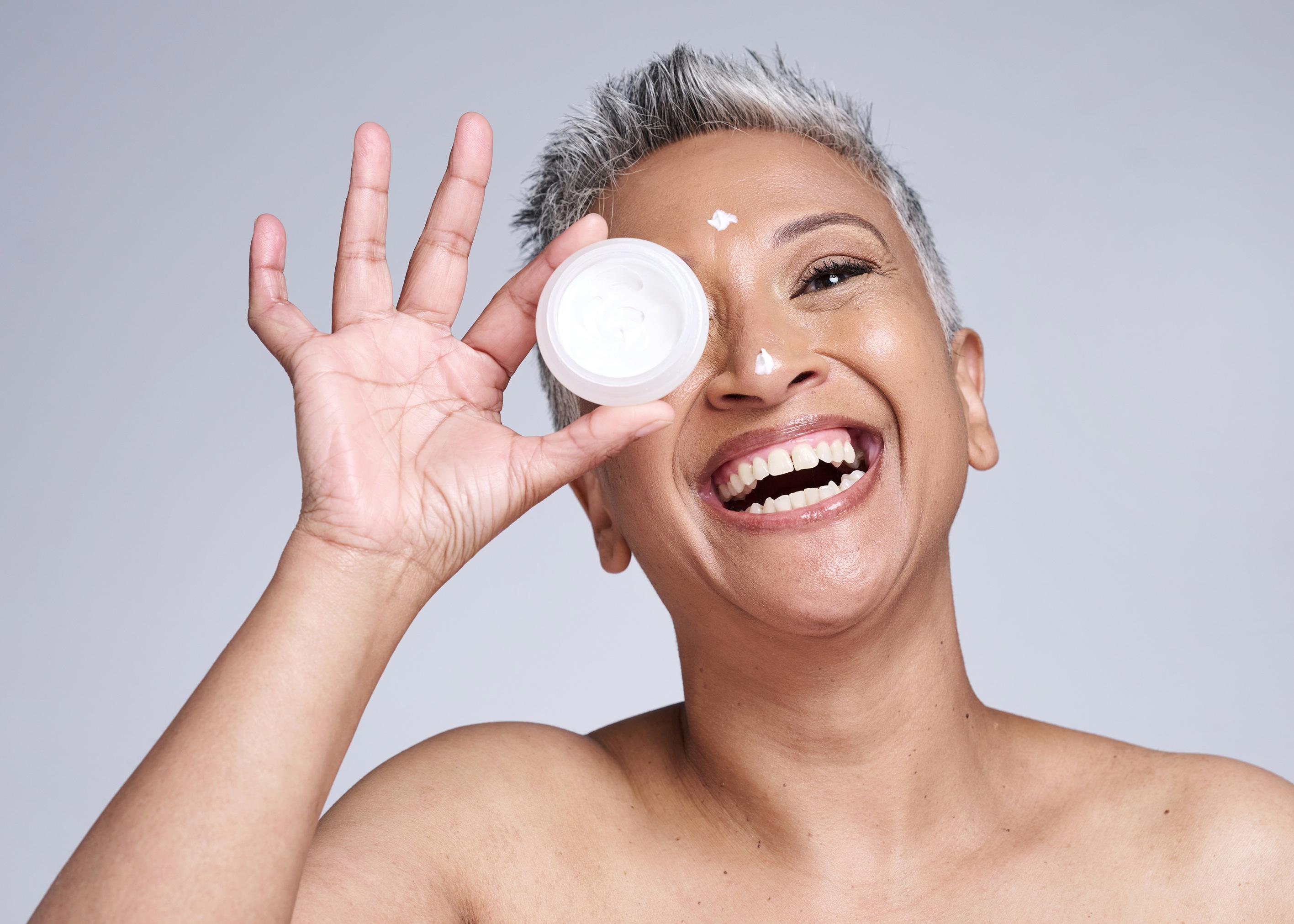 mature-woman-laughing-and-holding-a-tub-of-face-cream-in-front-of-her-eye_9447-x-6747px (1)