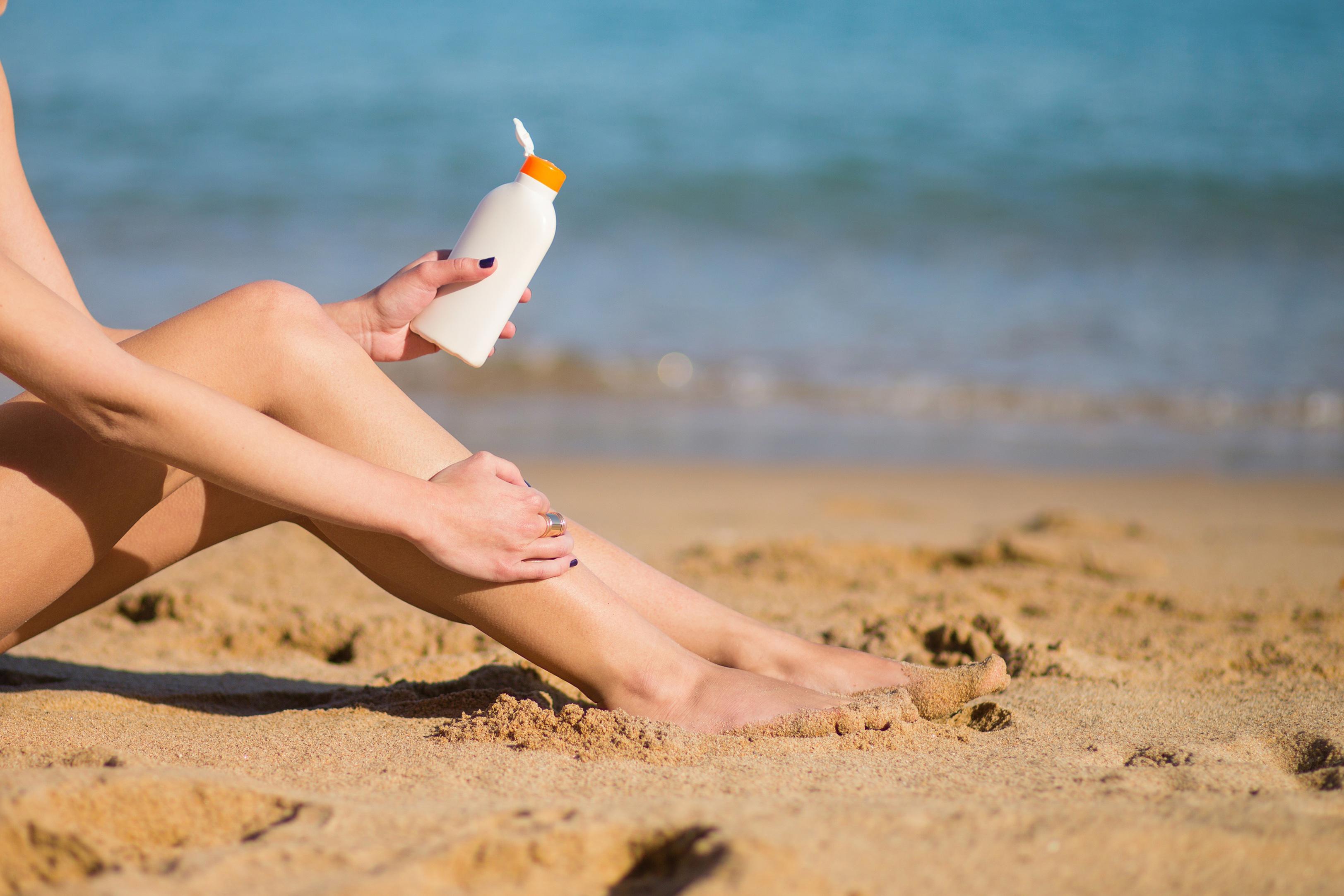 beautiful-young-woman-applying-sunscreen-on-her-legs-xl_6495x4330px