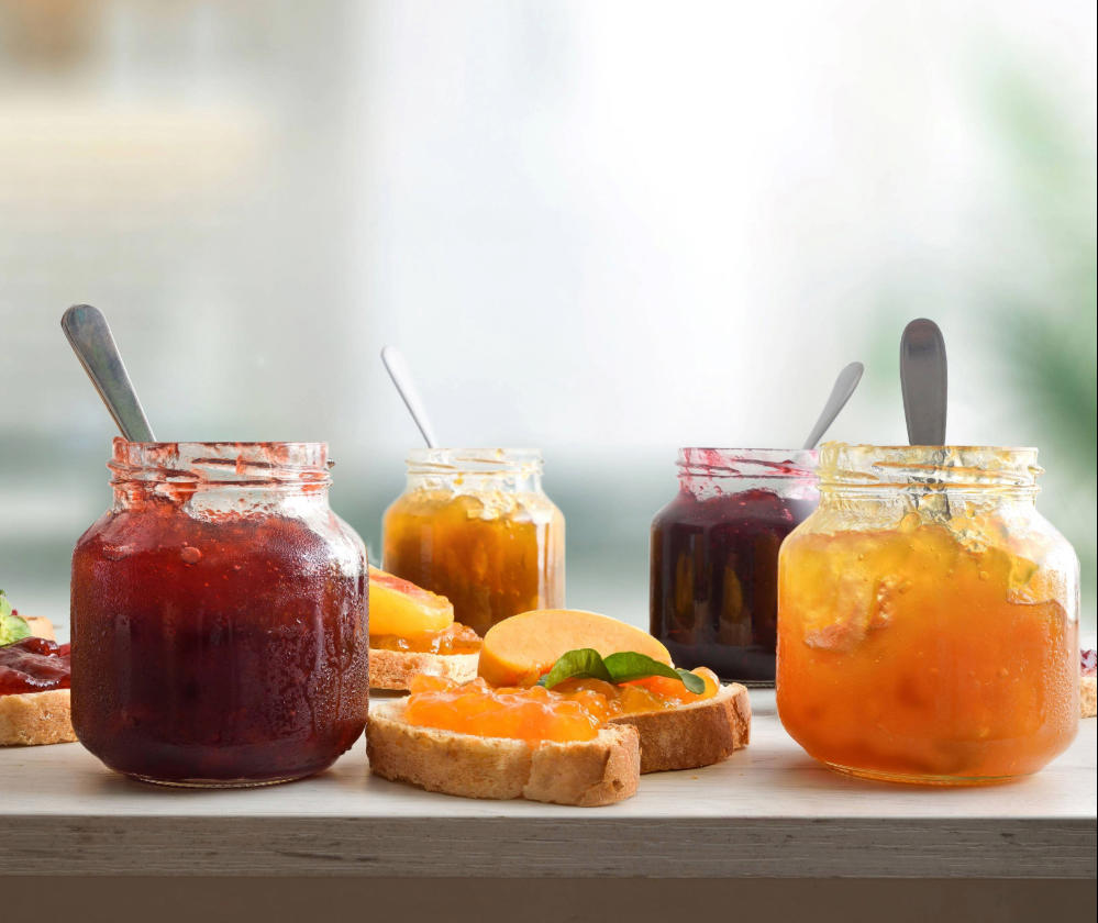 jars-full-of-jam-of-various-flavors-and-slices-of-bread-with-jam-decorated-and-kitchen-background_11034-x-1