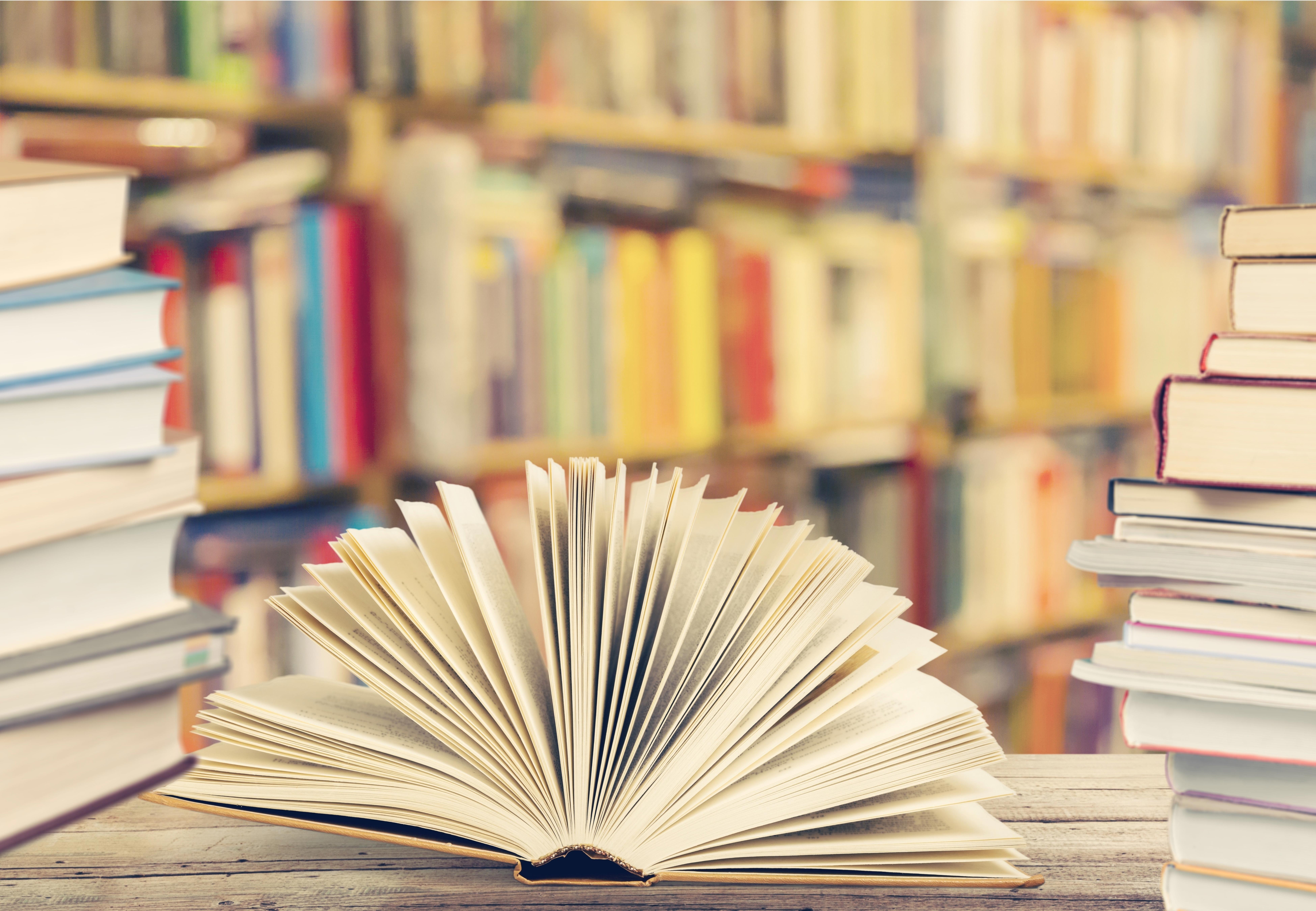 open-book-on-wooden-table-with-bookshelf-in-the-background_7800-x-5400-px