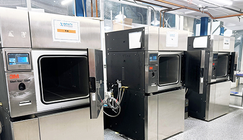 Trois machines industrielles de stérilisation alignées dans un environnement de laboratoire ou de production moderne chez Eurofins. La première, un modèle "3M Steri-Vac", est ouverte et révèle une chambre vide en acier inoxydable. Les deux autres machines sont fermées, équipées de panneaux de commande numériques. L’image illustre les installations de stérilisation avancées utilisées dans les processus pharmaceutiques, mettant en avant la rigueur et la technologie dans le contrôle de la contamination.