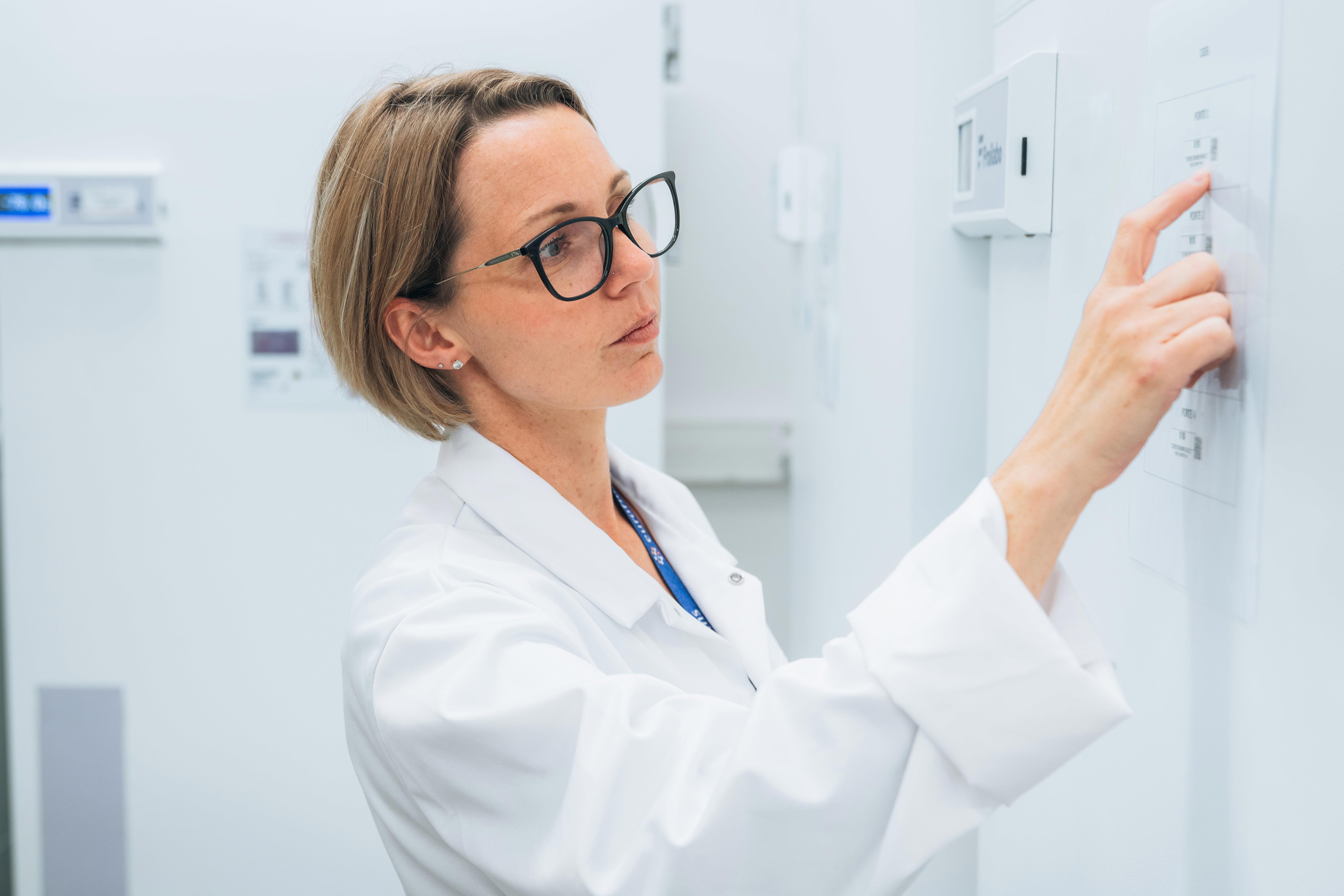 Technicienne de laboratoire en blouse blanche chez Eurofins BioPharma Product Testing, utilisant un écran de contrôle en environnement laboratoire pour l’analyse des données de stabilité.