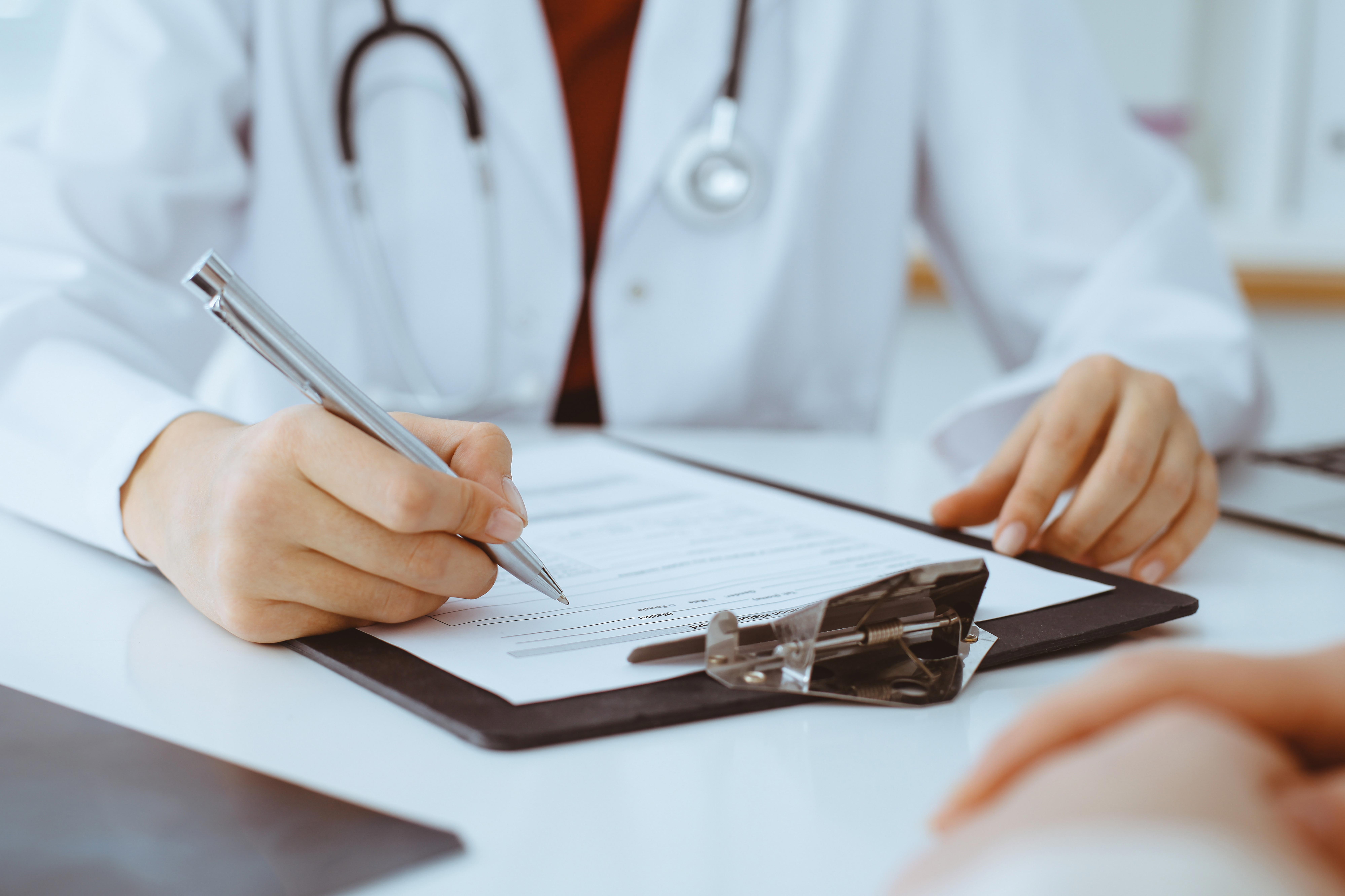 unknown-woman-doctor-filling-up-an-application-form-while-consulting-patient_7995-x-5329-px