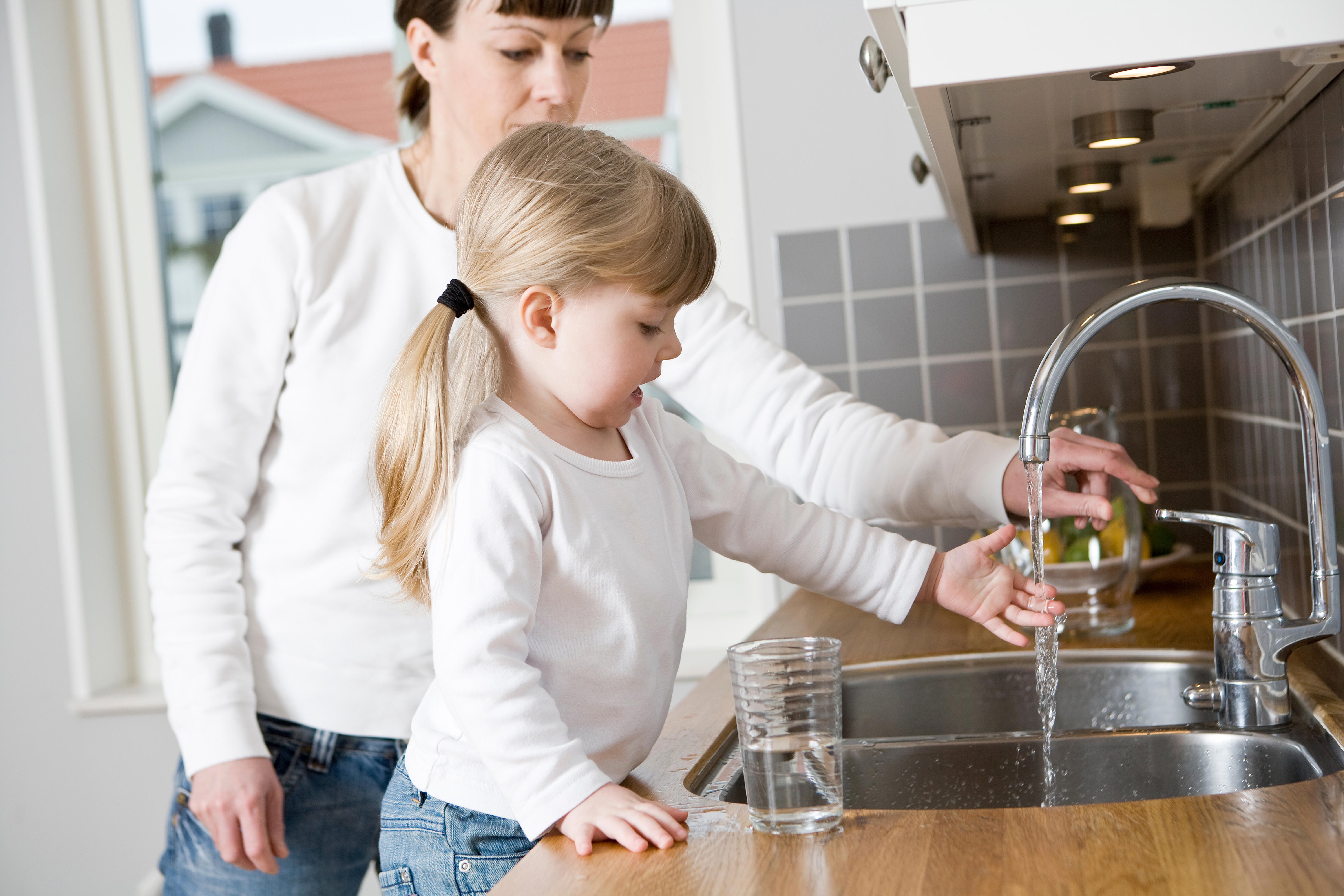 small-girl-in-the-kitchen-with-her-mother-drinking-water_6112-x-4075px