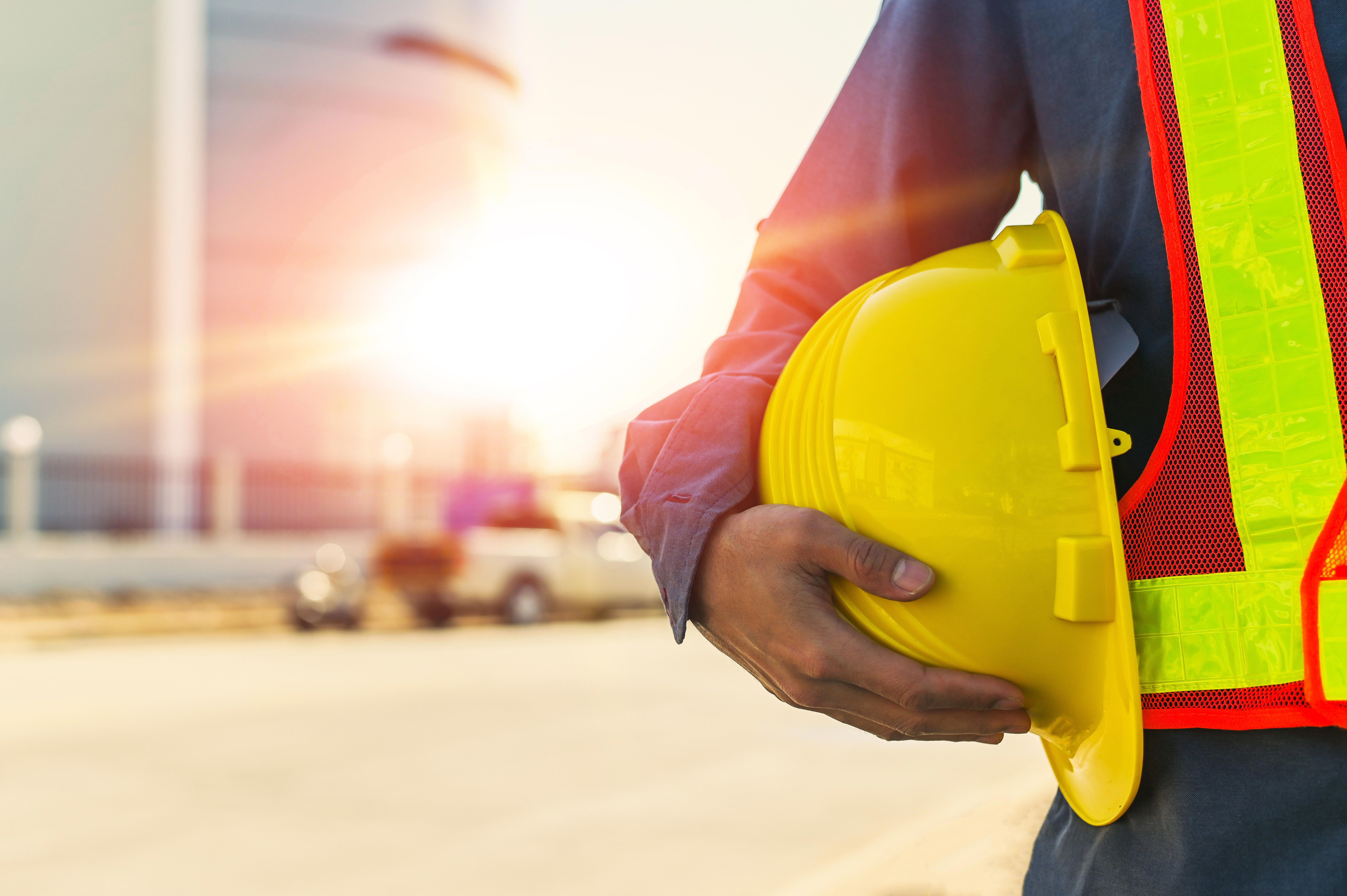 engineer-holding-safety-helmet-on-building-construction-site-background-with-sun-light_9072-x-6036-px_compressed