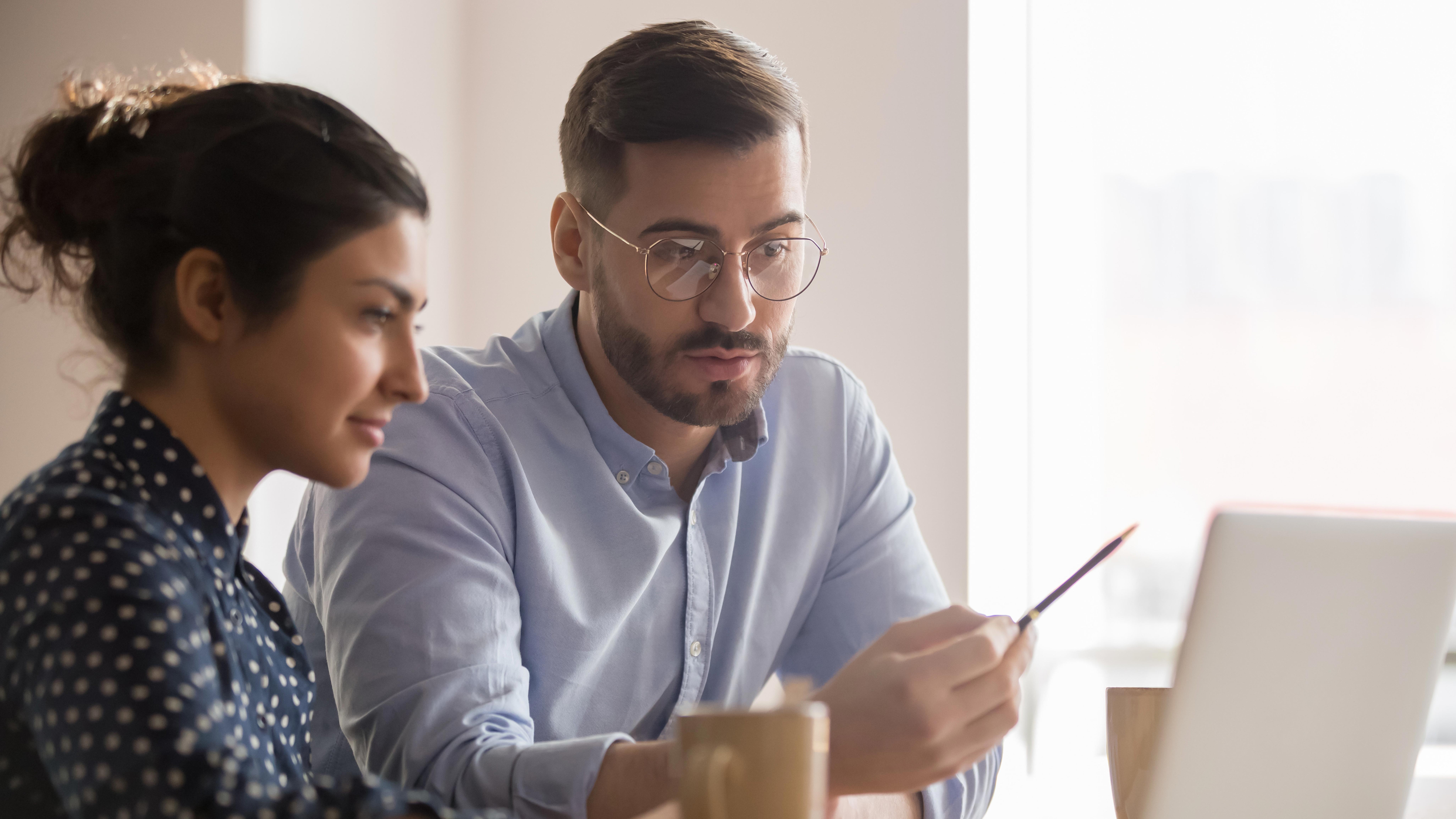 concentrated-male-businessman-looking-at-computer-monitor-working-with-a-female-worker-on-a-project_-8208-x-4617-px