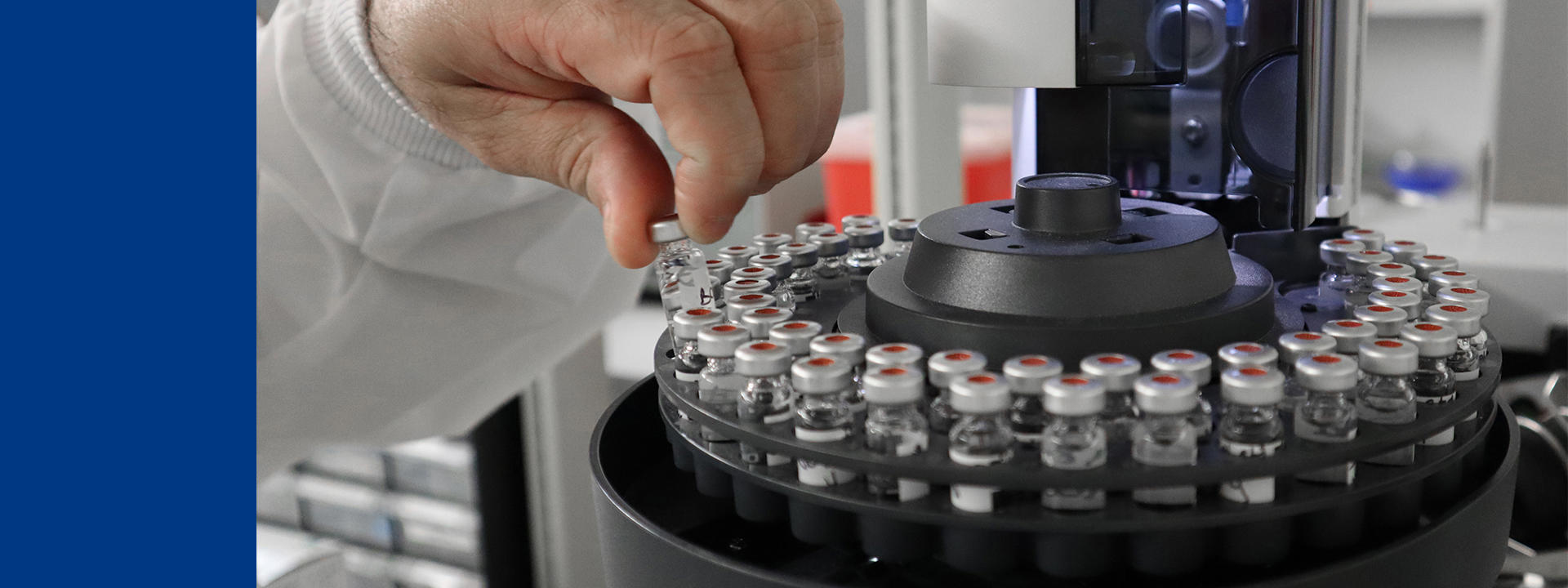 Technicien de laboratoire manipulant des flacons pharmaceutiques sur un système automatisé, illustrant les procédures de validation de la stérilisation, le contrôle qualité et la conformité aux BPF dans un environnement stérile.