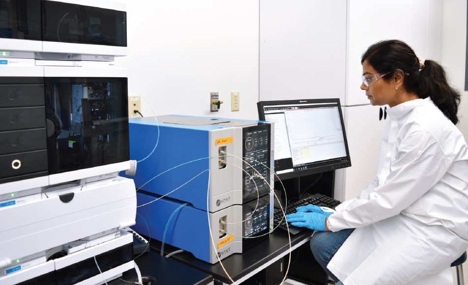 Technicienne de laboratoire Eurofins travaillant sur des instruments Agilent et Waters pour des analyses chimiques et chromatographiques, illustrant les services de bioanalyse et de contrôle qualité en environnement GMP