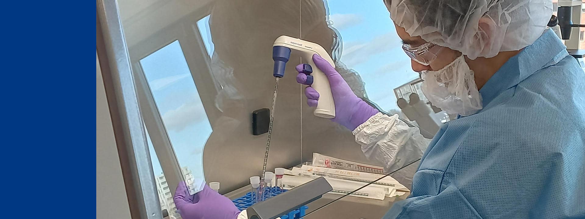Technicien de laboratoire chez Eurofins BioPharma Product Testing manipulant une pipette électronique sous hotte de sécurité biologique. L’opération se déroule dans un environnement stérile avec des gants, une charlotte et une blouse de protection. Sur la paillasse, des tubes et un rack sont disposés pour la préparation et le transfert d’échantillons, illustrant les procédures de sécurité appliquées aux tests biopharmaceutiques.
