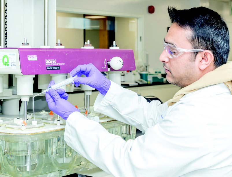 Technicien Eurofins BioPharma Product Testing utilisant un testeur de dissolution automatisé DIStek pour l’analyse de la libération de principes actifs, dans le cadre de tests de qualité pharmaceutique.