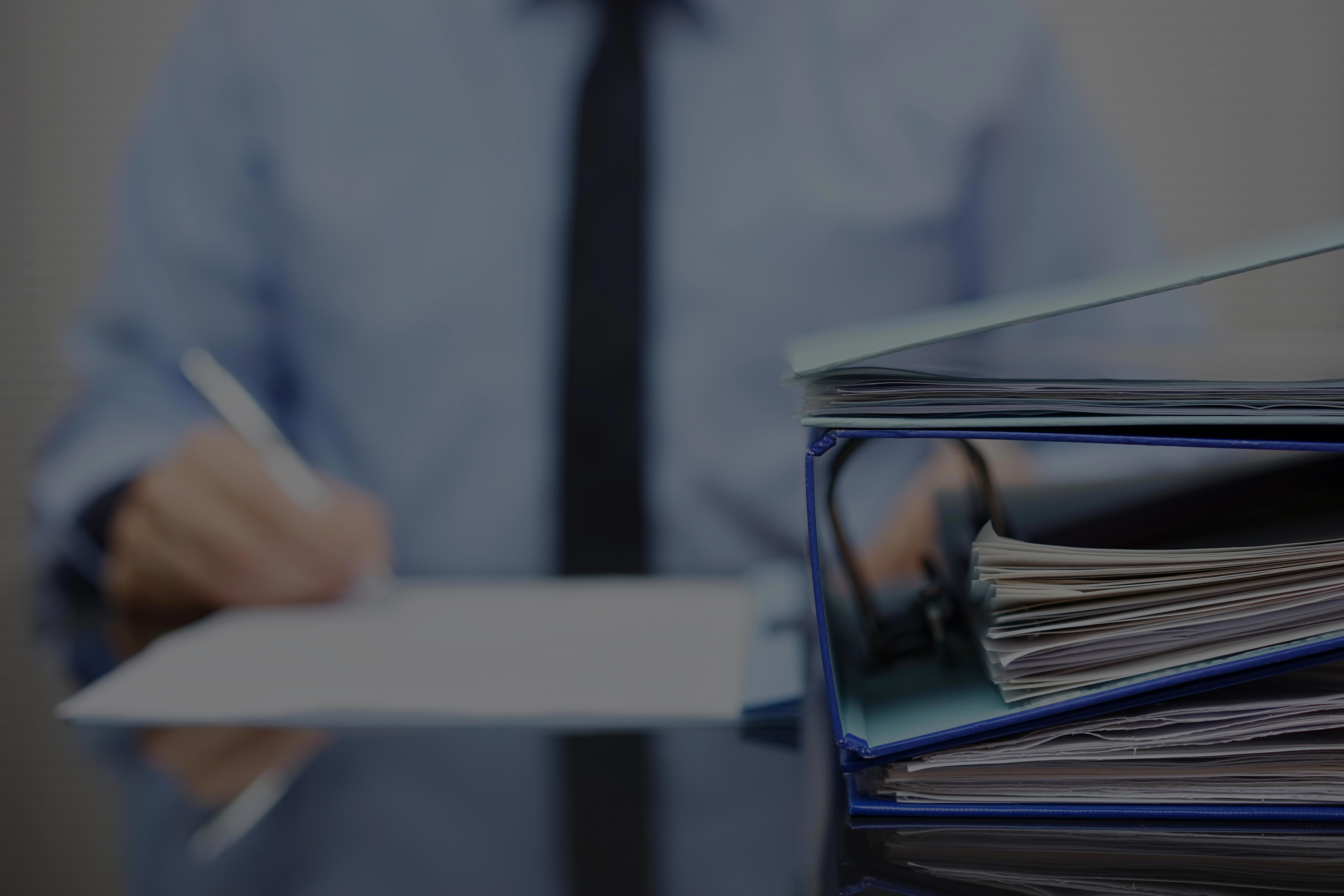 binders-with-papers-are-waiting-to-be-processed-with-businessman-back-in-blur-xl_9000x6000px-1 (1)
