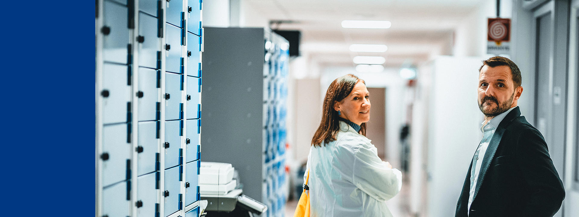 Personnel Eurofins Biopharma Services en blouse blanche et tenue professionnelle dans un couloir de laboratoire conforme aux BPF, illustrant les activités de contrôle qualité, de tests biopharmaceutiques et de conformité réglementaire. Environnement sécurisé dédié aux analyses microbiologiques, biochimiques et aux essais de biosécurité pour les produits pharmaceutiques et biotechnologiques.