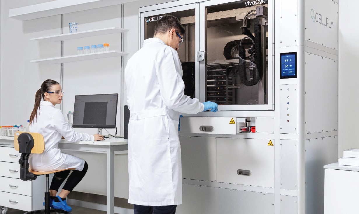 Deux collaborateurs en laboratoire Eurofins travaillent dans un environnement analytique. L’un est assis à un poste informatique, tandis que l’autre interagit avec un analyseur cellulaire VivaCyte de la marque CELLPly. Tous deux portent des blouses blanches et des gants bleus, illustrant les standards de sécurité et de précision appliqués lors des essais en laboratoire. En arrière-plan, des étagères contenant des flacons complètent l’environnement scientifique.