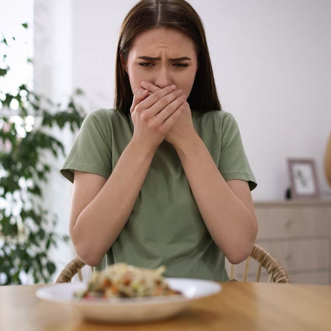 young-woman-feeling-nausea-while-seeing-food-at-wooden-table-indoors_648