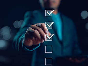 Personne en costume interagissant avec une interface numérique de checklist, illustrant la validation de tâches, l’application de lignes directrices et la gestion de projet digitale dans un environnement professionnel.