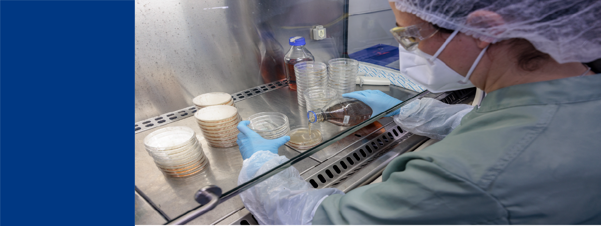 Technicienne de laboratoire Eurofins Biopharma Product Testing travaillant sur un système analytique de chromatographie liquide installé sur une paillasse. L’environnement montre un laboratoire moderne avec des équipements scientifiques, des flacons de réactifs, un ordinateur et des affiches techniques au mur.