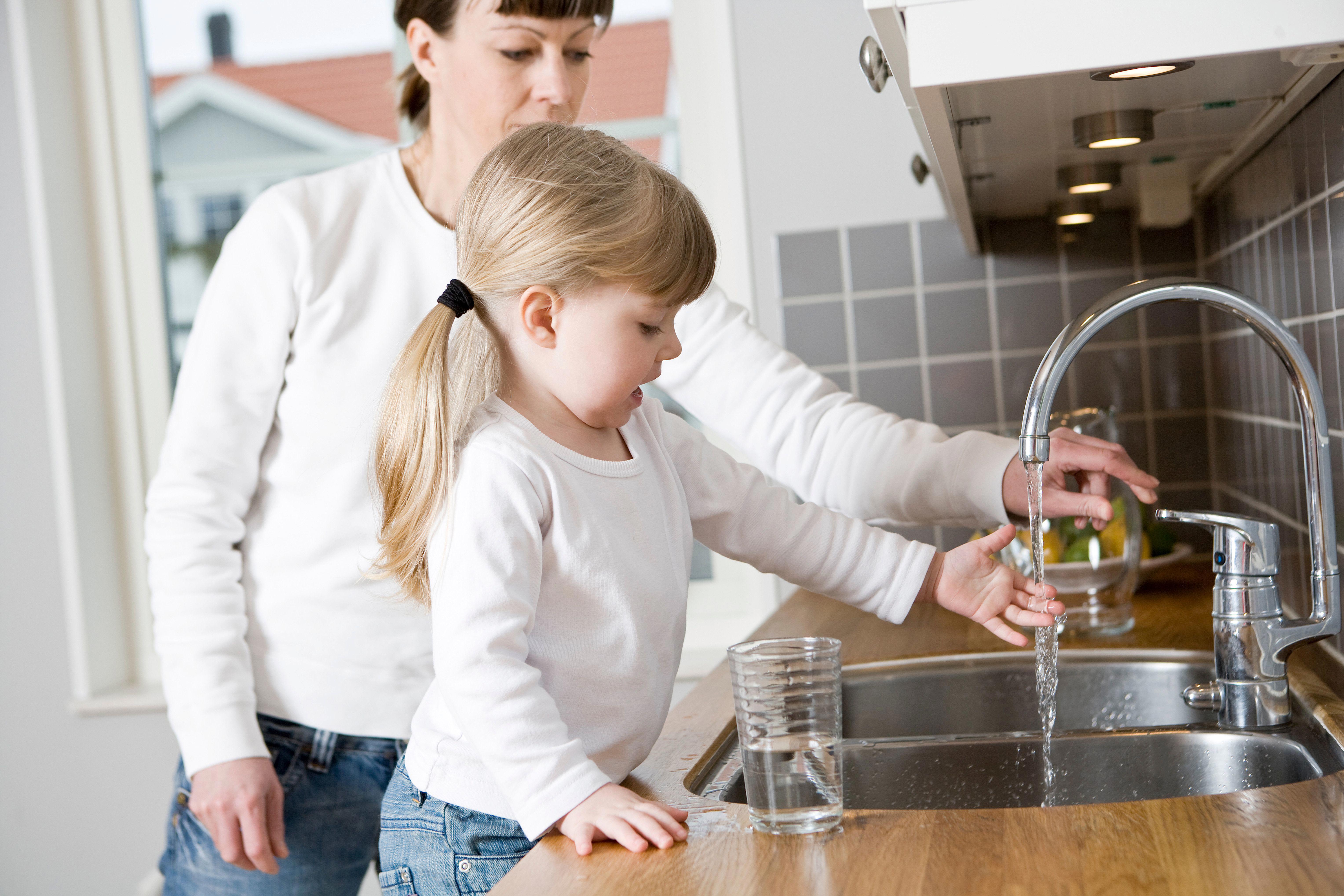 small-girl-in-the-kitchen-with-her-mother-drinking-water_6112-x-4075px-l