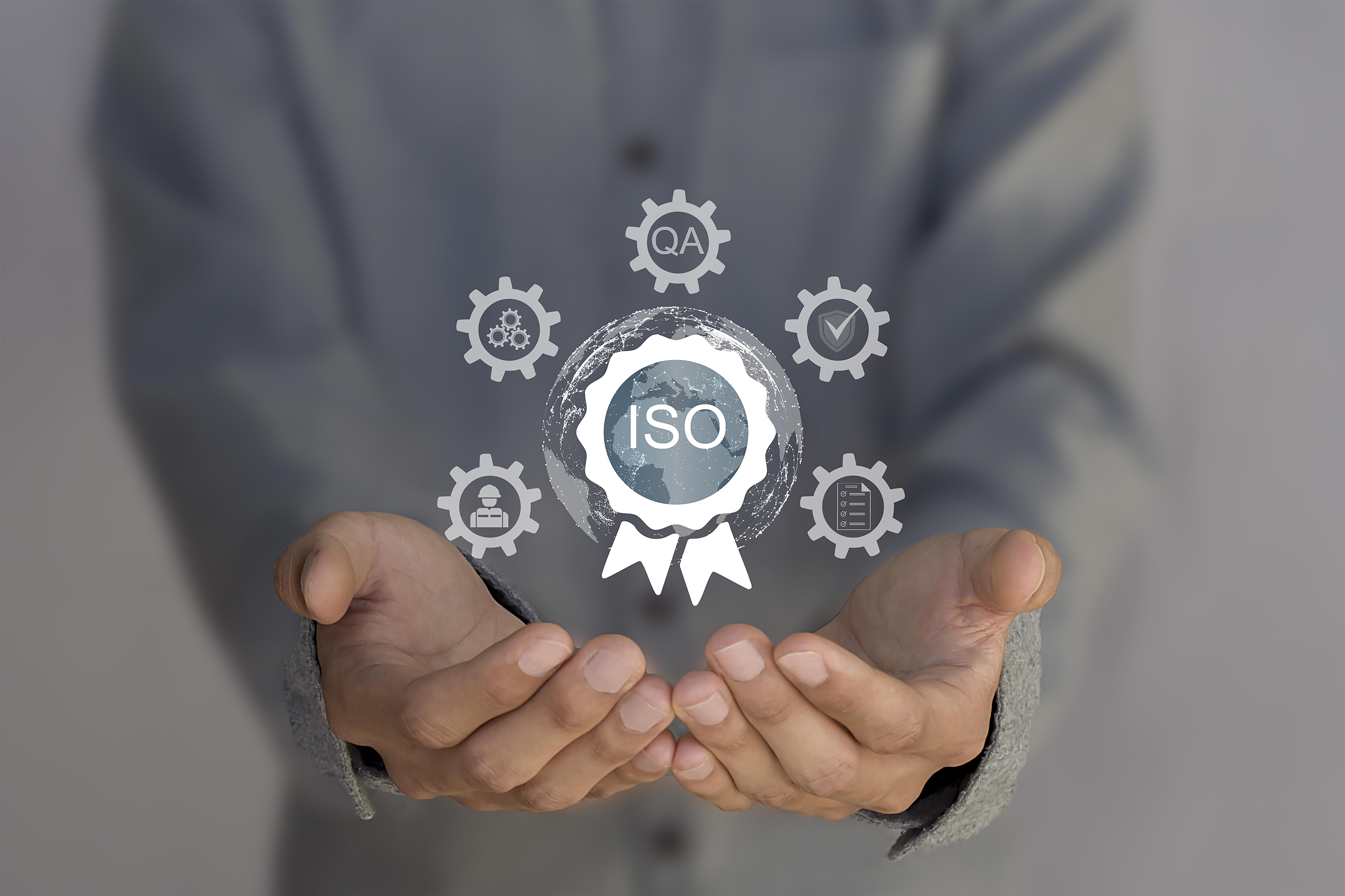 des-mains-tenant-un-badge-de-certification-iso-avec-des-icones-d-engrenage
