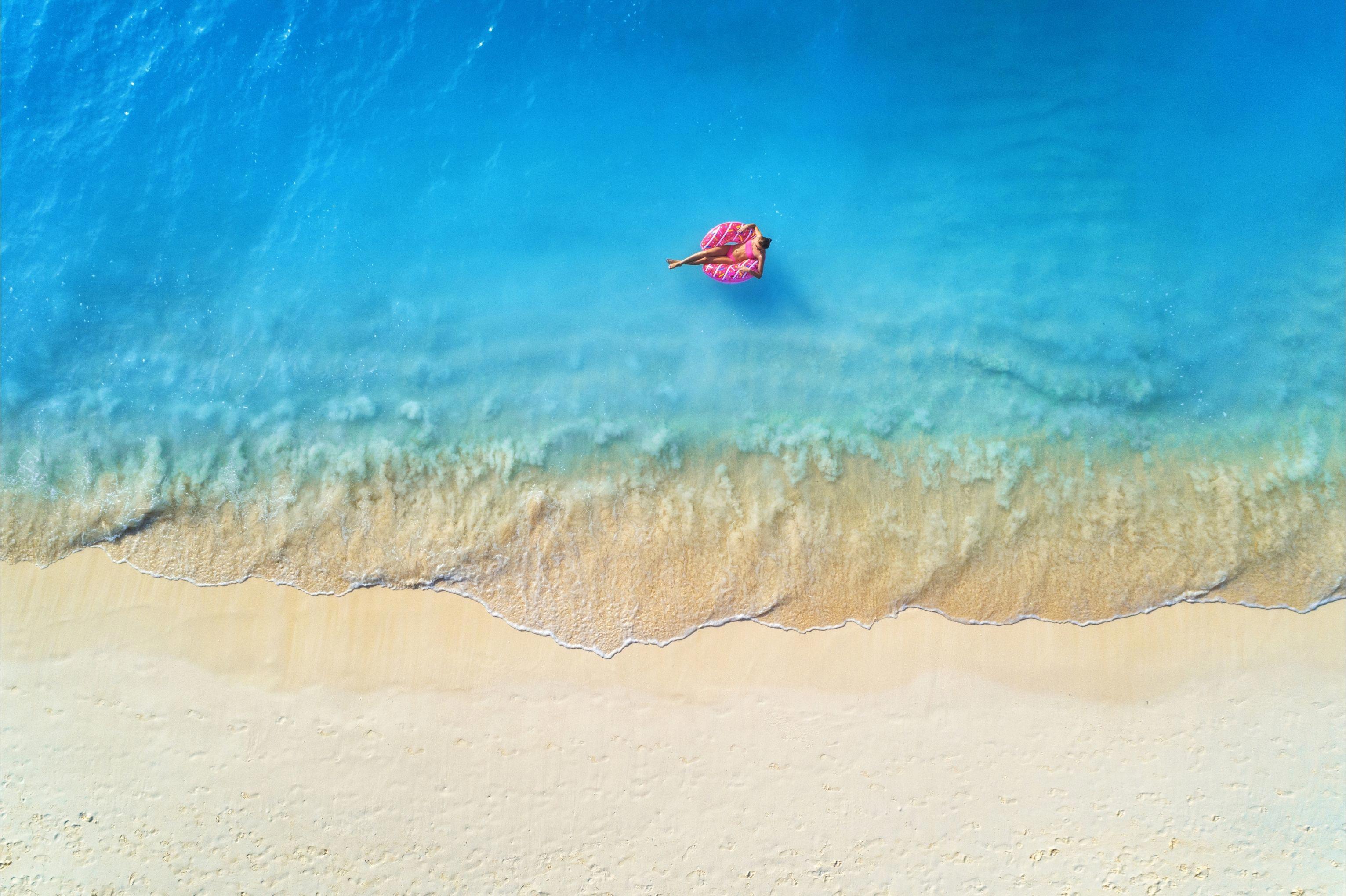 aerial-view-of-a-young-woman-swimming-with-the-donut-swim-ring_8196-x-5460-px-1