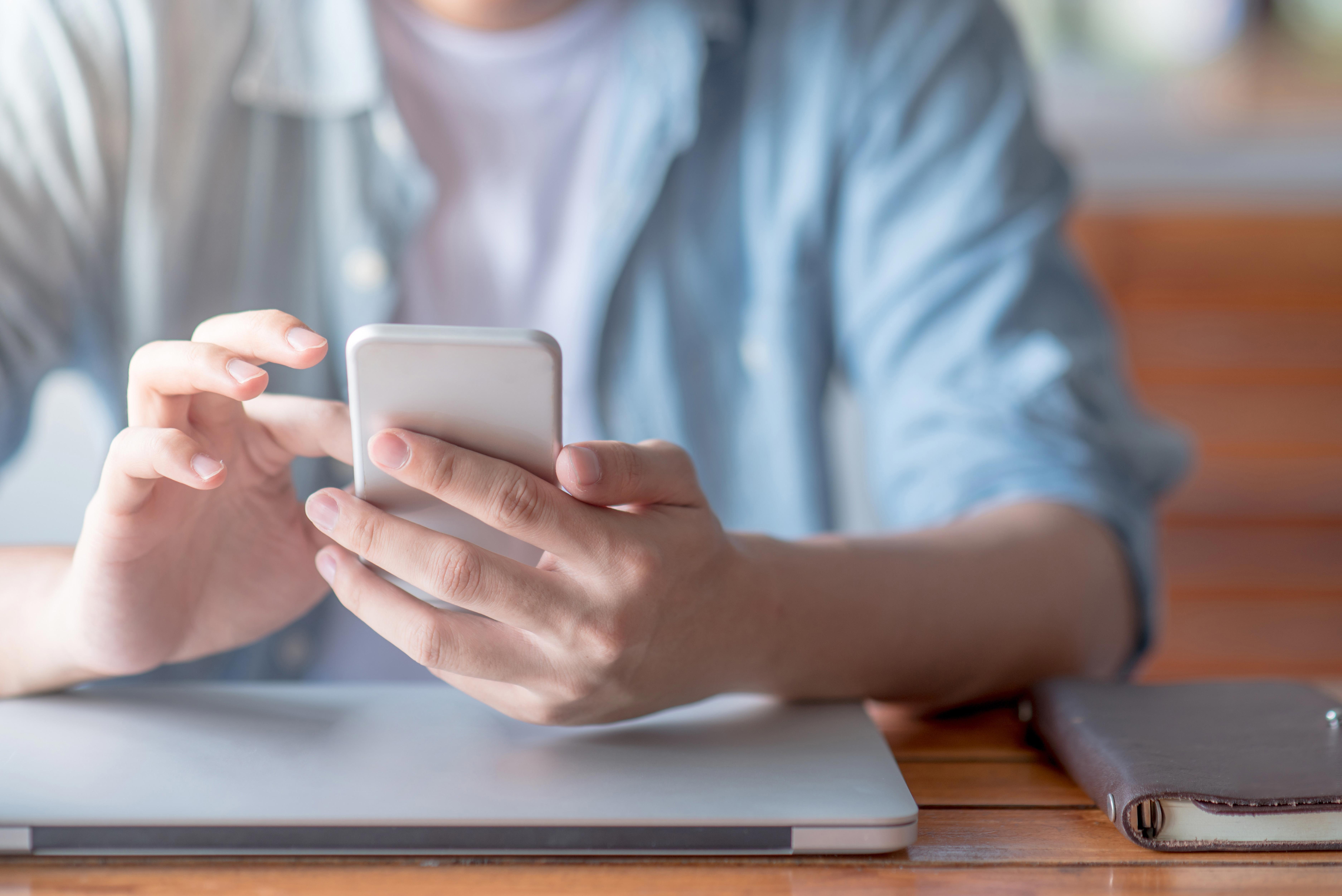 closeup-image-of-a-man-using-mobile-smart-phone-while-sitting-at-the-table_7500-x-5007-px