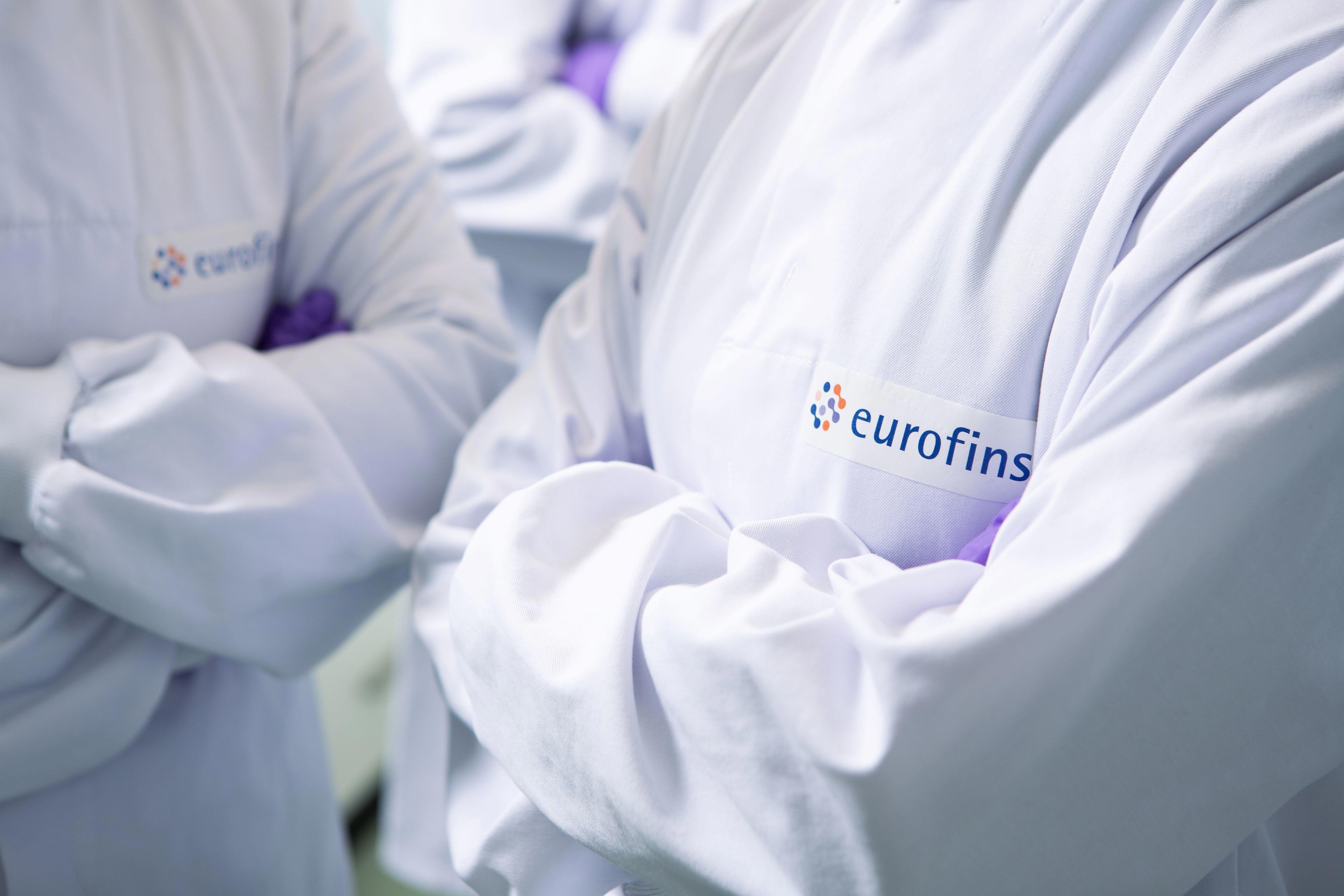 Techniciens de laboratoire en blouse blanche logotée Eurofins, dans un laboratoire conforme aux normes GMP, ISO 9001 et ISO 14001. Illustration de l’expertise en analyses pharmaceutiques, environnementales, alimentaires et cliniques, avec engagement qualité, traçabilité et conformité réglementaire.