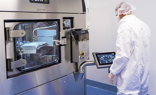 Opérateur en environnement stérile utilisant une machine Vanrx pour le remplissage aseptique de flacons pharmaceutiques. L’équipement, doté d’une interface tactile & d’une chambre en acier inoxydable visible à travers une vitre, permet un conditionnement automatisé & sécurisé de médicaments injectables. Cette technologie, intégrée dans les processus de Eurofins BioPharma Product Testing, garantit une conformité stricte aux normes BPF & une maîtrise optimale de la contamination particulaire & microbiologique