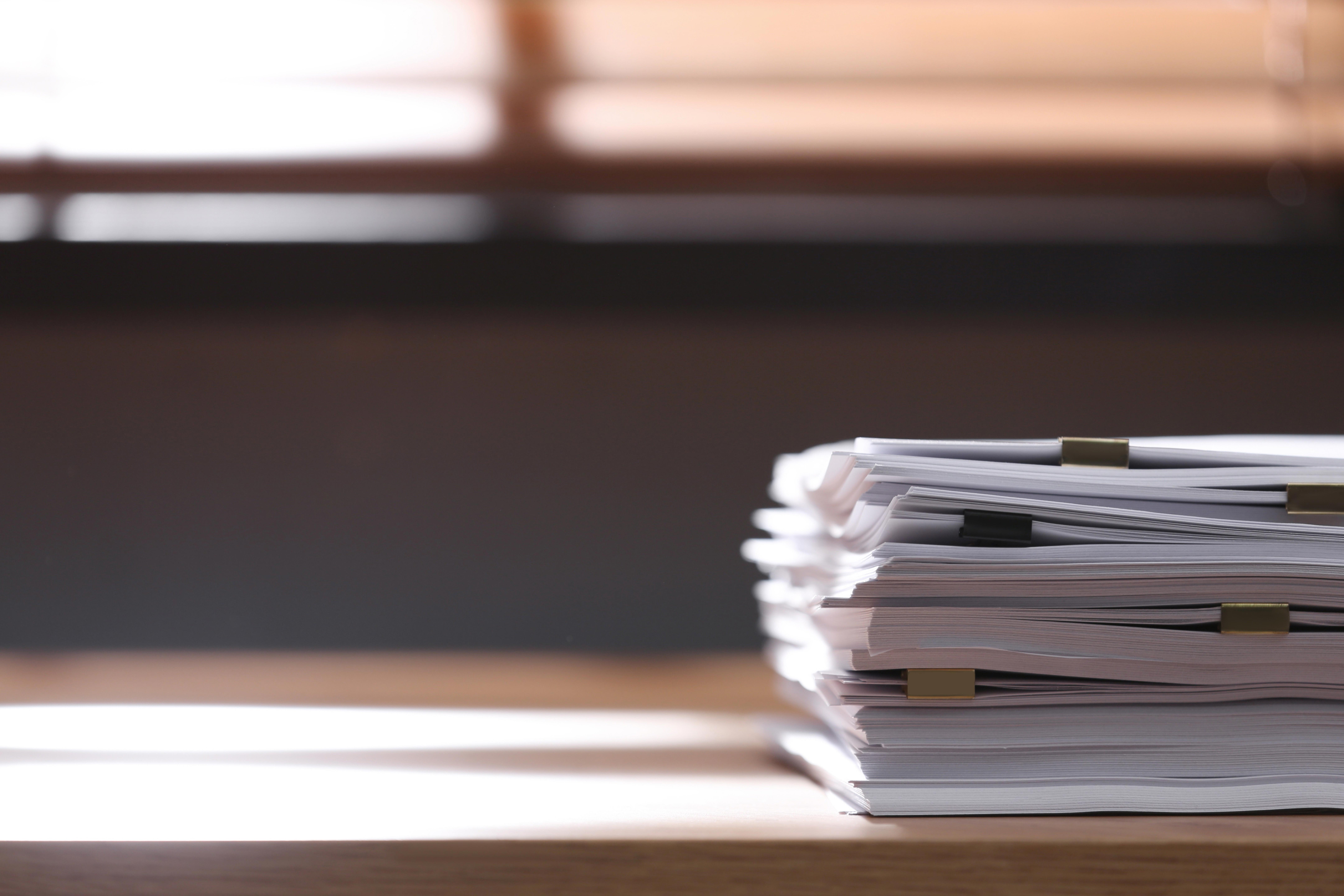 stack-of-blank-paper-with-binder-clips-on-wooden-table-indoors