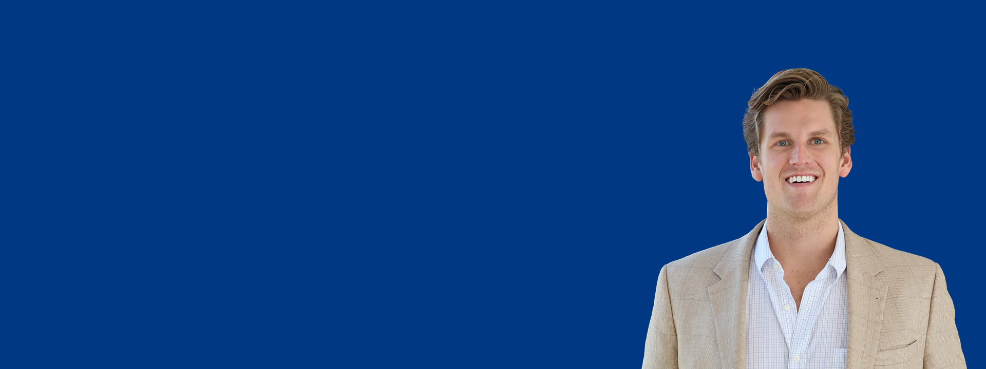 Portrait-style image of a professional individual wearing a light-colored blazer and white shirt, standing against a solid dark blue background with ample empty space on the left side for text or design elements.